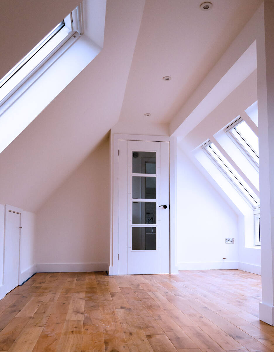 Loft bedroom with oak floor and glazed door